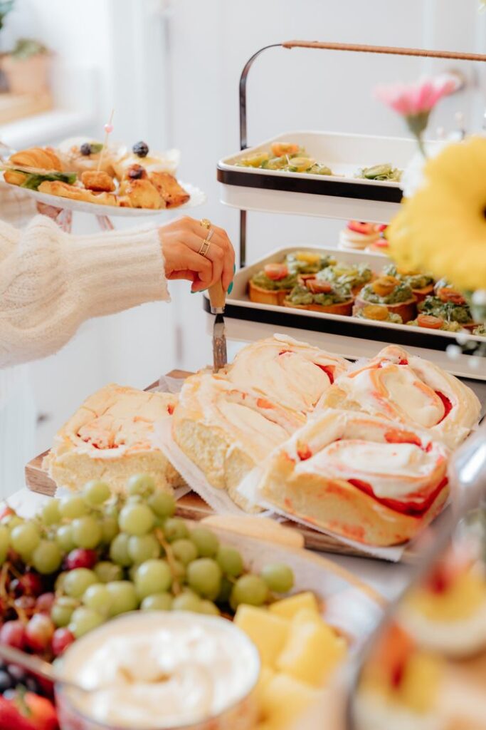 A buffet spread with fresh pastries, sandwiches, fruits, and appetizers in a cozy setting.