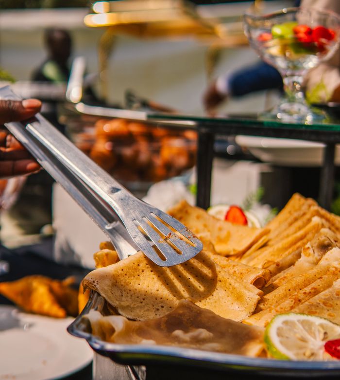 A vibrant outdoor buffet showcasing delicious crepes and fresh fruits in a sunny setting.